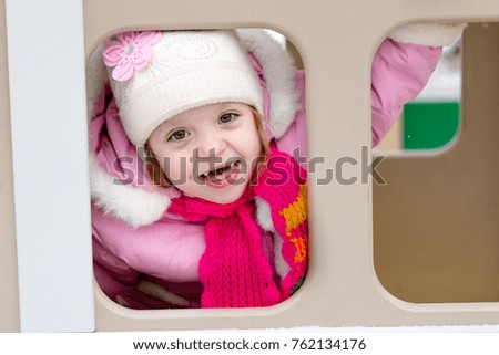 girl playing on a children's playground in winter