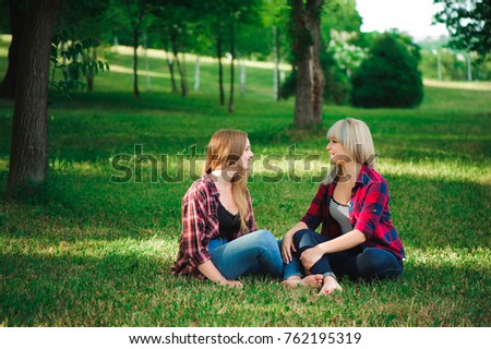 lifestyle and people concept: Two young girl friends sitting together and having fun.