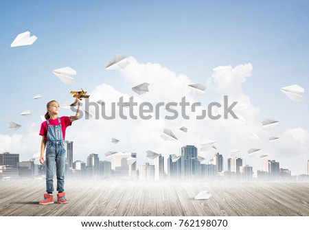 Cute kid girl stand on wooden floor and paper planes flying around