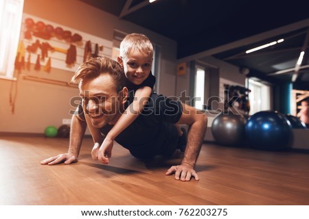 Father and son in the gym. Father and son spend time together and lead a healthy lifestyle. Man and boy are working out. Father and son are doing exercise. Royalty-Free Stock Photo #762203275