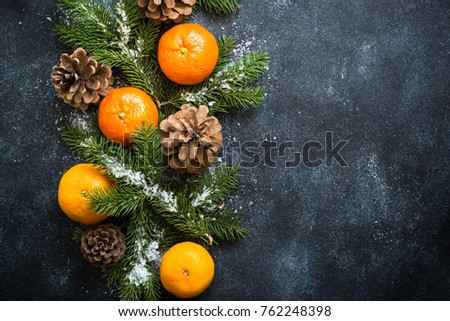 Traditional christmas background with fir tree, tangerines and pine cones at black stone table. Top view copy space.