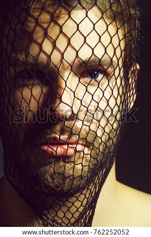 Young man blond bearded male with beard or robber bandit gangster wears mask of black fishnet stocking on face on dark background