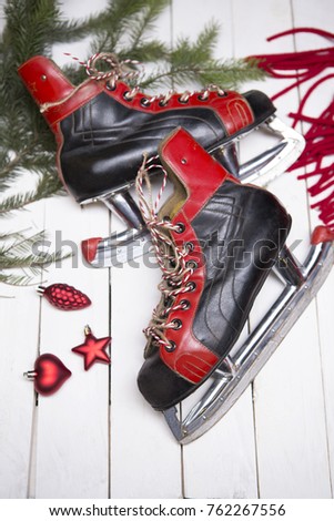 Christmas and New Year's card - vintage skates in the New Year's decor - fur-tree branch, red scarf, toys. Top view, shot on a white wooden background. Red, white, green colors.