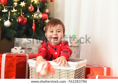 Happy baby and New Year's decoration. Baby with gifts. Baby in the basket