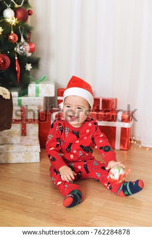 Happy baby and New Year's decoration. Baby with gifts. Baby with Santa's hat