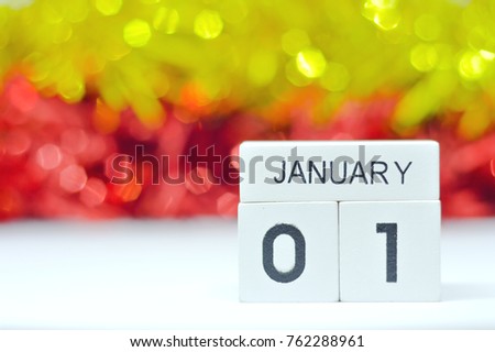 White wood block calendar,black alphabets, January the first on white floor with red and yellow glitter blur bokeh background,copy space for add text, things in your idea concept for New Year festival
