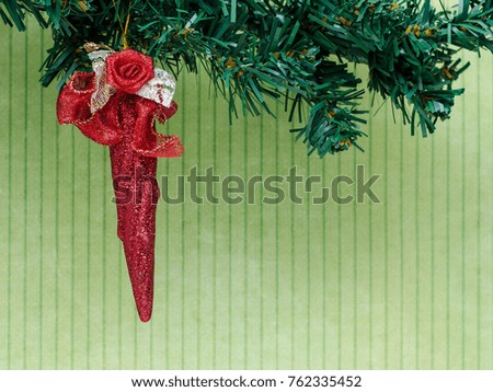 Red christmas decoration on the branch of artificial christmas three. 


Green striped background