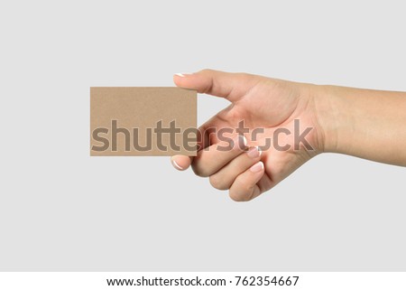 Mockup of female hand holding a Kraft Paper Business Card isolated on light grey background. Size 85x 55 mm.