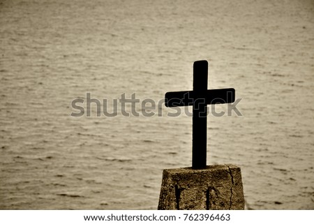 Dark silhouette of metal cross with the sea as a background