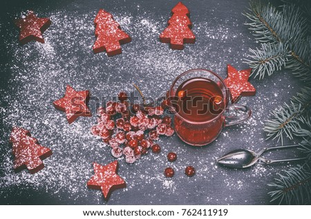 tea from berries of a viburnum in a transparent mug on a black background and festive decor, vintage toning