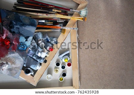  tubes of oil paints of different colors with brushes of different sizes and palette on  background, a bunch of tubes
