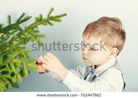 Five-year-old red-haired boy hangs the decor on a branch of a Christmas tree. Preparation for Christmas and New Year.