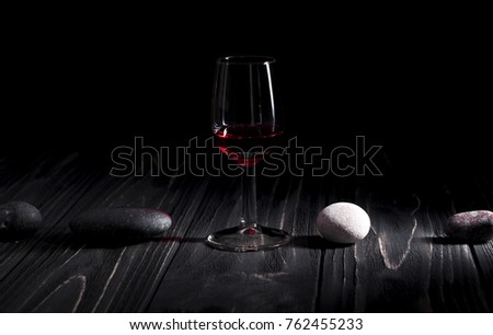 Glass of red wine on black background and on a wooden desk