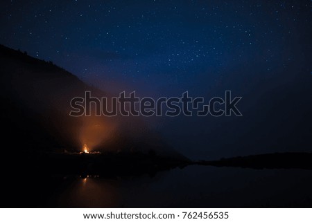 Landscape on the shore of the lake in the Carpathians at the night with bonfire