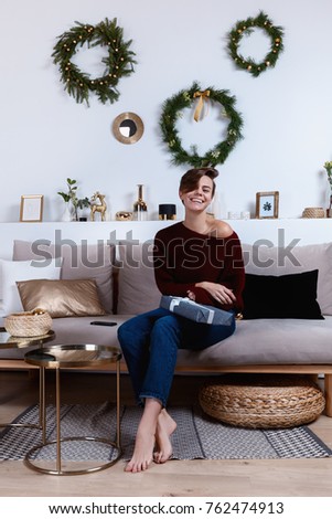 Young woman is preparing presents for the xmas and new year. Photo is made in a holiday interior