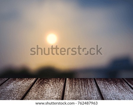 Wood table foreground montage with sun and sunlight and sky with blur picture background as copy space concept in sunset time