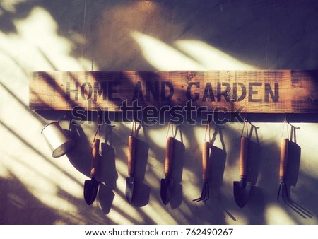Garden tools hanging on the wall with wooden sign for decoration in vintage style and afternoon light on.