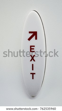 Red and white exit sign with arrow on an aircraft door