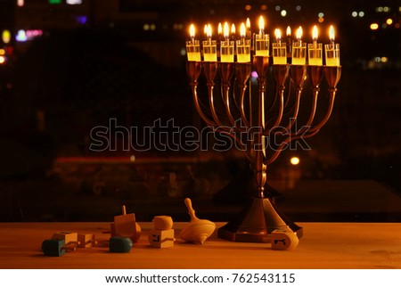 image of jewish holiday Hanukkah background with menorah (traditional candelabra) and burning candles in front of the window