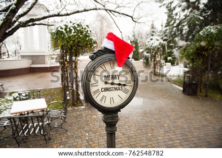 vintage street clock with the inscription Merry Christmas and Santa Claus hat on them in town winter street