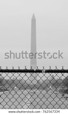 Black and white image of wire fence with Washington Monument Obelisk on the background. Concept editorial image.