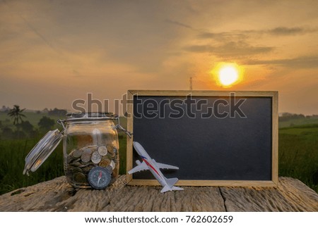 Saving planning for Travel budget of holiday concept,Financial, coins money in the jar, compass and airplane wooden table with sunrise background