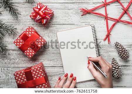 Goals plans dreams make to do list for new year christmas concept writing in notebook. Woman hand holding pen on notebook with fir branches gift on white background. New year winter holiday xmas Royalty-Free Stock Photo #762611758