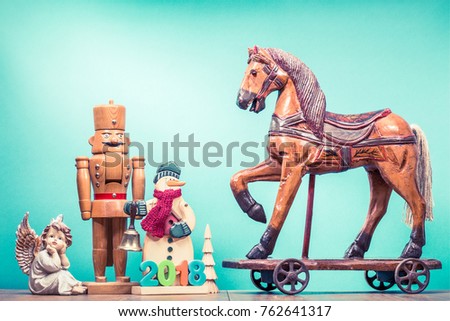Retro antique Christmas wooden horse on wheels toy, old snowman with jingle bell and 2018 date, nutcracker, little New Year tree and angel. Holiday greeting card. Vintage style photo