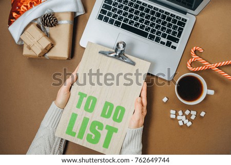 Planning concept. Woman hands with To do list and laptop on brown office table. Top view, Flat lay