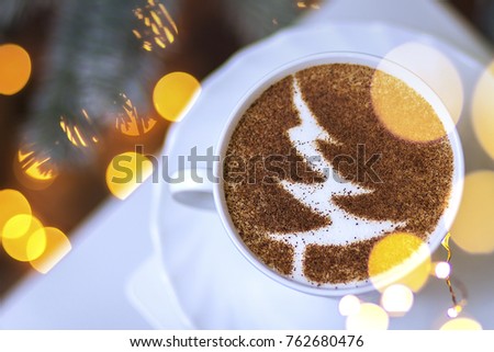 Christmas coffee in a white cup with a picture of a New Year tree from cinnamon on milky foam cappuccino