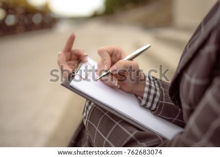 Woman writes something on paper, starts to write a letter, a document, signs papers using a pen. Person sign document, write on paper using pen.