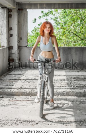 Girl on bike on the background of an abandoned factory building