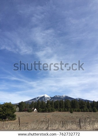 Portrait picture of a snow capped mountain beneath a large sky