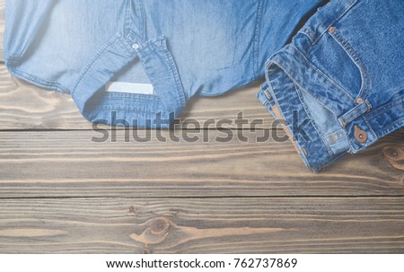 Jeans trousers and jeans shirt on a wooden surface. Top view.
