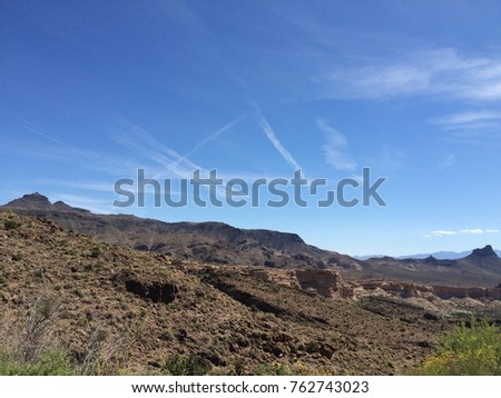 Landscape picture of a blue sky with white contrails over rocky and desert landscape shot near Kingman in Arizona, USA