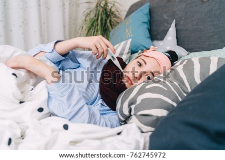 Sick woman in bed with thermometer is having high temperature/fever Royalty-Free Stock Photo #762745972