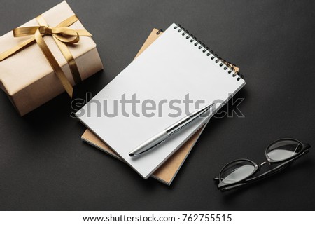 school notebook with gifts on a black background, gift boxes with spiral notepad on a table