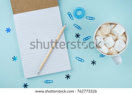 Creative flat lay photo of workspace desk with smartphone, eyeglasses, pen, pencil and notebook, minimal style on blue background. Minimal business concept. Chtistmas shopping concept, with cocoa