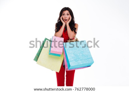 I need that shoes! Beautiful young woman holding shopping bags and looking shocked while standing against white background