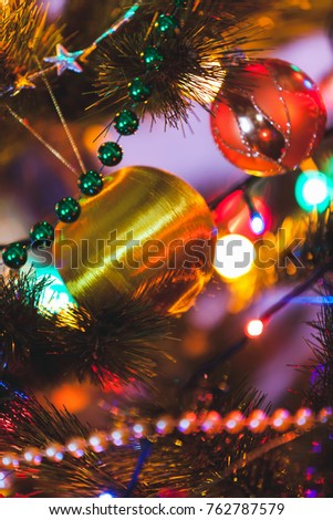 bright yellow ball weighs on a green branch fir close up. Around blurry lights and garland

