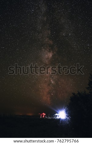Illuminated tent on the beach against the background of a bright sky with milky way.