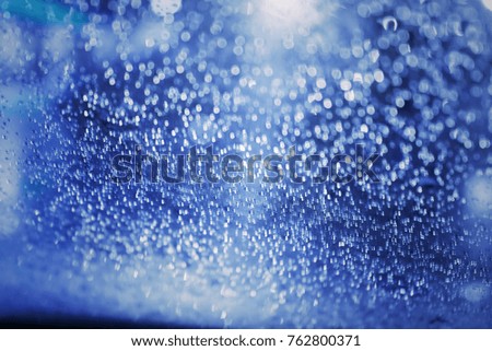 Rain water drops blue background. Defocused blur texture with bokeh.