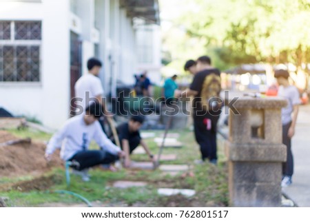 a blurred people repairing sidewalk. Worker laying stone paving slab.