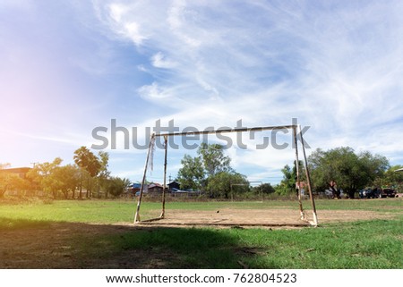  soccer goal without net empty field , trees and clear sky background.