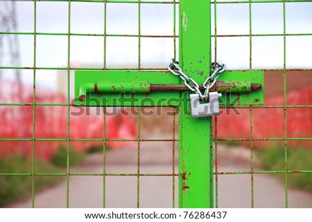 green construction site gate closed with chain and padlock