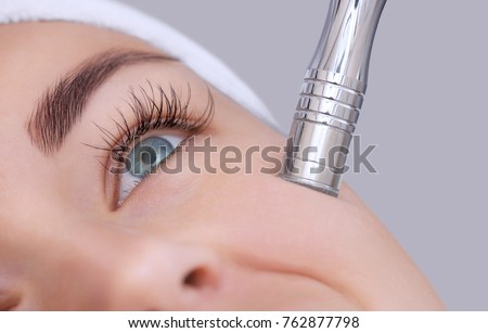 The cosmetologist makes the procedure Microdermabrasion of the facial skin of a beautiful, young woman in a beauty salon.Cosmetology and professional skin care. Royalty-Free Stock Photo #762877798