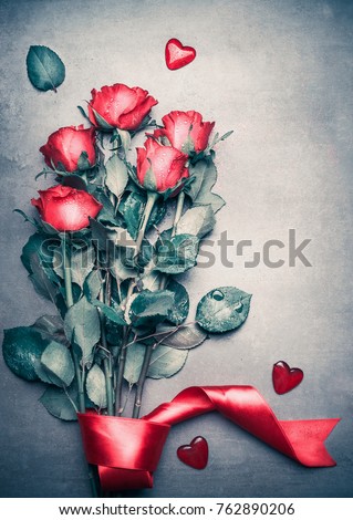 Red roses bouquet with ribbon and hearts on gray desktop background, top view. Layout for Valentines day, dating , love greeting card, anniversary and invitations