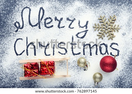 Inscription Merry Christmas on wheat flour background with baubles and gift boxes