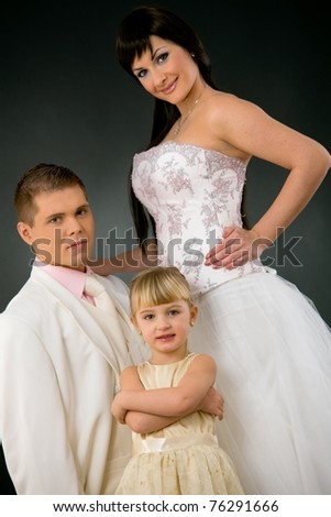 Portrait of wedding couple and little girl bridesmaid. Bride wearing romantic white wedding dress, groom in white suit.?