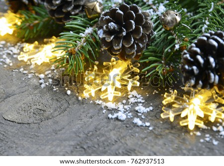 Christmas decoration with garland lights,pine cones and fir tree on old wooden background.Winter holidays concept.Copy space.